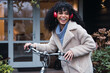 © Frenchiebuddha - Enthusiastic woman afro riding bicycle listening to music on headphones