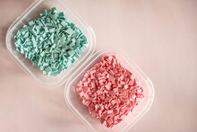 A pile of plastics - small pieces of hard plastic, pink and blue color, intended for further processing