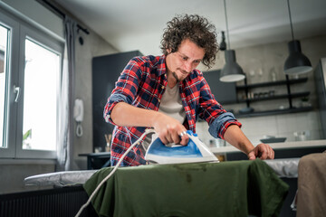 one man ironing clothes at home hold iron household chores concept