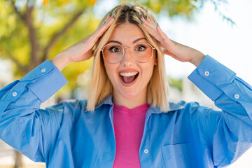 Young pretty woman with glasses at outdoors with surprise expression