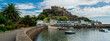 Panoramic image of Mont Orgueil Castle in Gorey on the island of Jersey in the Channel Islands. Fishing boats and colourful buildings with sunshine and blue sky