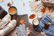 stylish modern winter or fall woman clothes set top view. Trendy shoes, sweaters and accessories in beige and blue tones with Christmas lights and autumn leaves.