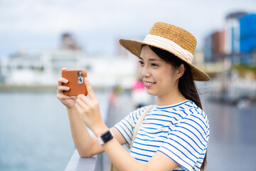 Wall Mural - Travel woman use mobile phone take photo in Keelung harbor