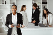 © Prostock-studio - African american CEO businesswoman posing with digital tablet in front of her colleagues working on background