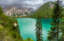Braies Lake Surrounded By Pine Forests And The Rocky Ranges Of The Dolomites In Cloudy Day, Italy.