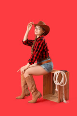 Poster - Young cowgirl sitting on red background