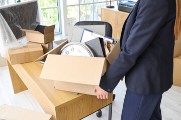 Poster - Businesswoman holding cardboard box with personal belongings in office on moving day