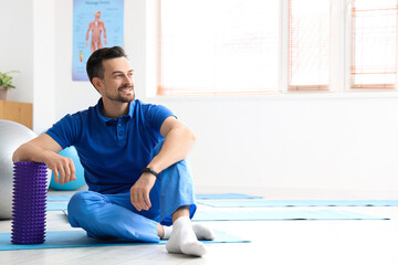 Wall Mural - Male physiotherapist with foam roller in rehabilitation center