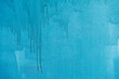 Dirty painted wall surface, flowing paint of blue bright color, texture. Abstract background