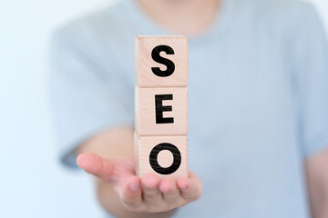 Man holding cubes vertically with SEO text on it, website concept, search engine optimization idea, wooden block cubes with SEO word, banner design