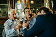 © Marko Geber - Diverse group of male businessman having a beer and celebrating closing a deal on their job