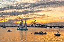 Sailboats At Rest In Newport Rhode Island Harbor As A Peaceful Sun Sets Behind The Newport Bridge