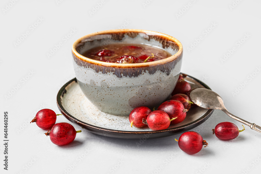Bowl with tasty gooseberry jam on white background