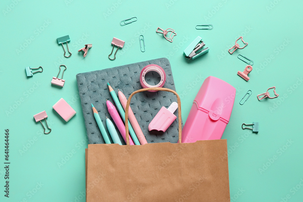 Composition with paper bag and different stationery on turquoise background