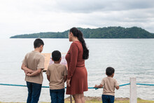Latino Family Standing With Their Backs To Each Other Reading A Sign At The Seaside