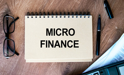 Text MICRO FINANCE written on a Notepad on a business or financial topic. Top view of the calculator, documents, and desktop.Business concept