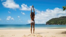A Woman Standing On A Beach With Her Arms Raised