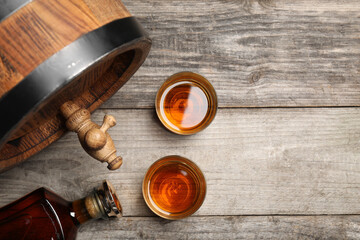 Wall Mural - Glasses and bottle of whiskey with wooden barrel on table, flat lay. Space for text