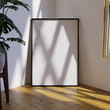 © themagia - frame mockup poster on the wooden floor in the corner of the living room leaning on the white wall