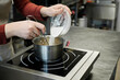 © TrueFrame Collective - Unrecognizable female confectioner adding powdered sugar to fruit topping being cooked in saucepan in restaurant kitchen