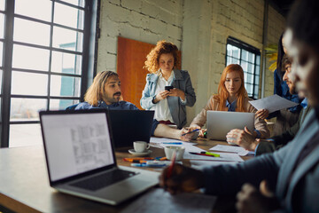 Wall Mural - Young and diverse group of coworkers working on a project and having a meeting in a startup company office