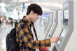 Man, airport and self service for check in, ticket registration or online boarding pass. Male traveler by terminal machine or kiosk for travel application, document or booking flight for plane trip