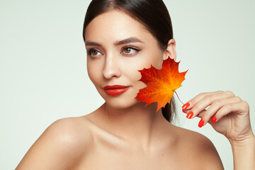 Portrait of beautiful young woman with autumn leafs. Healthy clean fresh skin natural make up beauty eyes and red nails