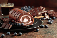 Chocolate Roll Cake With Blueberries And A Broken Chocolate Bar.