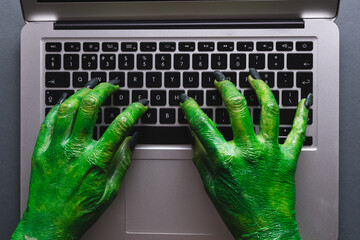 Poster - Green monster hands writing on laptop keyboard on grey background