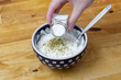 Doprawiać solą i ziołami biały sos w miseczce 