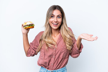 Wall Mural - Young pretty Uruguayan woman holding a burger isolated on white background with shocked facial expression