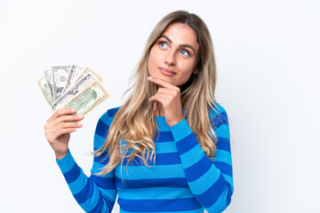 Canvas Print - Young Uruguayan woman taking a lot of money isolated on white background and looking up