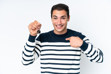 Wall Mural - Young caucasian man holding home keys isolated on white background with surprise facial expression