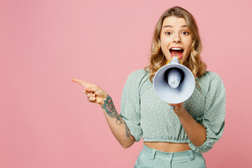 Young shocked excited happy woman wear casual clothes hold in hand megaphone scream announces discounts sale Hurry up point finger aside isolated on plain pastel light pink background studio portrait.