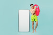 Full body young man in green shorts relax near hotel pool hold ring big huge blank screen area mobile cell phone scream in megaphone isolated on plain blue background Summer sea rest sun tan concept