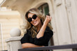 © Svetlana Sokolova - Beautiful smiling blond woman in elegant luxury sunglasses posing on the street. European background. Perfect wavy hairs.