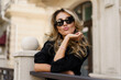© Svetlana Sokolova - Beautiful smiling blond woman in elegant luxury sunglasses posing on the street. European background. Perfect wavy hairs.