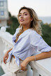 © Svetlana Sokolova - Beautiful  charming blond woman with perfect skin and wavy hairs  posing outdoor during vacation in  Europe.  Wearing blue blouse and white pants.  Summer fashion.