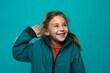 © Markus Schröder - Headshot portrait photography of a joyful kid female making a telephone call gesture with the hand against a teal blue background. With generative AI technology