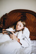 © Анна Молько - a girl in a bathrobe plays on the phone in bed