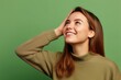 © Markus Schröder - Close-up portrait photography of a happy girl in her 20s putting the hand on the forehead to look for someone in the distance against a pastel green background. With generative AI technology