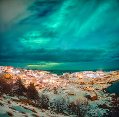 Wall Mural - Aurora borealis glowing over scandinavian village on coastline in winter at Lofoten Islands,