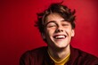 Lifestyle portrait photography of a beautiful boy in his 20s winking against a burgundy red background. With generative AI technology