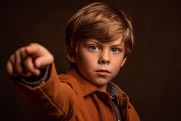 Wall Mural - Close-up portrait photography of a glad kid male pointing with two hands and fingers to the side against a copper brown background. With generative AI technology