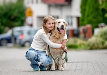 Sticker - Preteen girl with golden retriever dog sitting at city street and looking back. Pretty child kid with purebred pet doggy outdoors