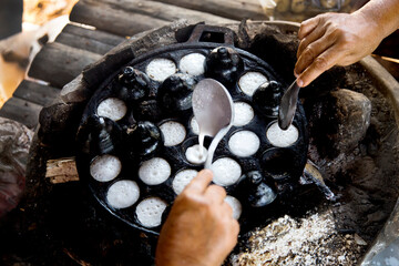 Wall Mural - Woman preparing coconut thai desserts. Kanom krok is a tasty Thai coconut milk based mini pancakes popular street food as well.