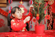young girl was decorating Chinese New year greeting card against with traditional Chinese 