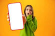 Teen girl showing smartphone screen with copy space over yellow background