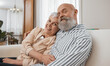 © Wesley/peopleimages.com - Smile, portrait and senior couple on a sofa in the living room of modern home for bonding. Happy, love and elderly man and woman in retirement hugging and relaxing together in the lounge of a house.