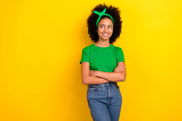Wall Mural - Photo of dreamy charming girl dressed green t-shirt hairband arms folded looking empty space isolated yellow color background